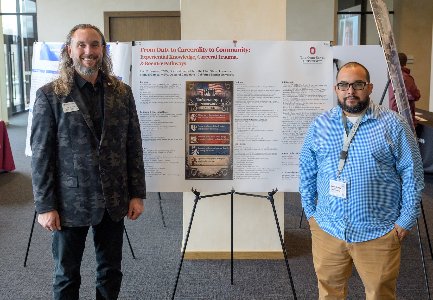 Dr. Manuel Gomez and Eric Sowers standing either side of their research poster, From Duty to Carcerality to Community, at a conference.
