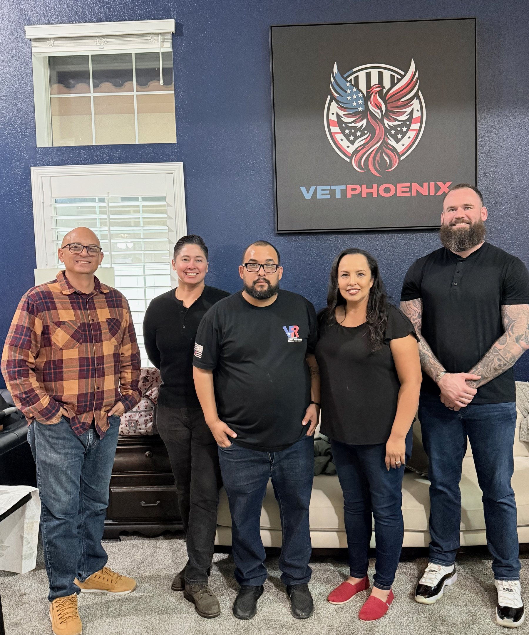 Five members of the VetPhoenix team standing beneath the VetPhoenix sign at the house.