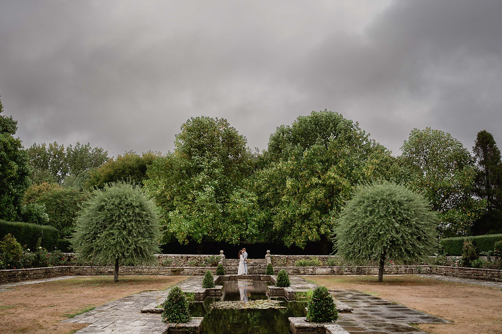 A panoramic image of the bride and groom kissing by the pond at Hinton St Mary Estate, Dorset.