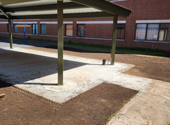 Commercial grounds with dirt grounds surrounding an awning awaiting to be hydroseeded