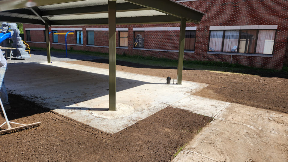 Commercial grounds with dirt grounds surrounding an awning awaiting to be hydroseeded