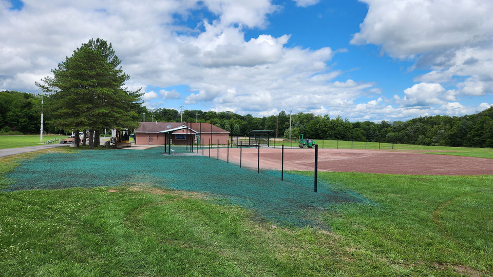 Freshly laid hydroseed on the grounds next to a baseball field