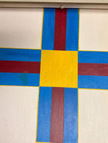 A painted red, blue, and yellow 'X' on a wooden board.