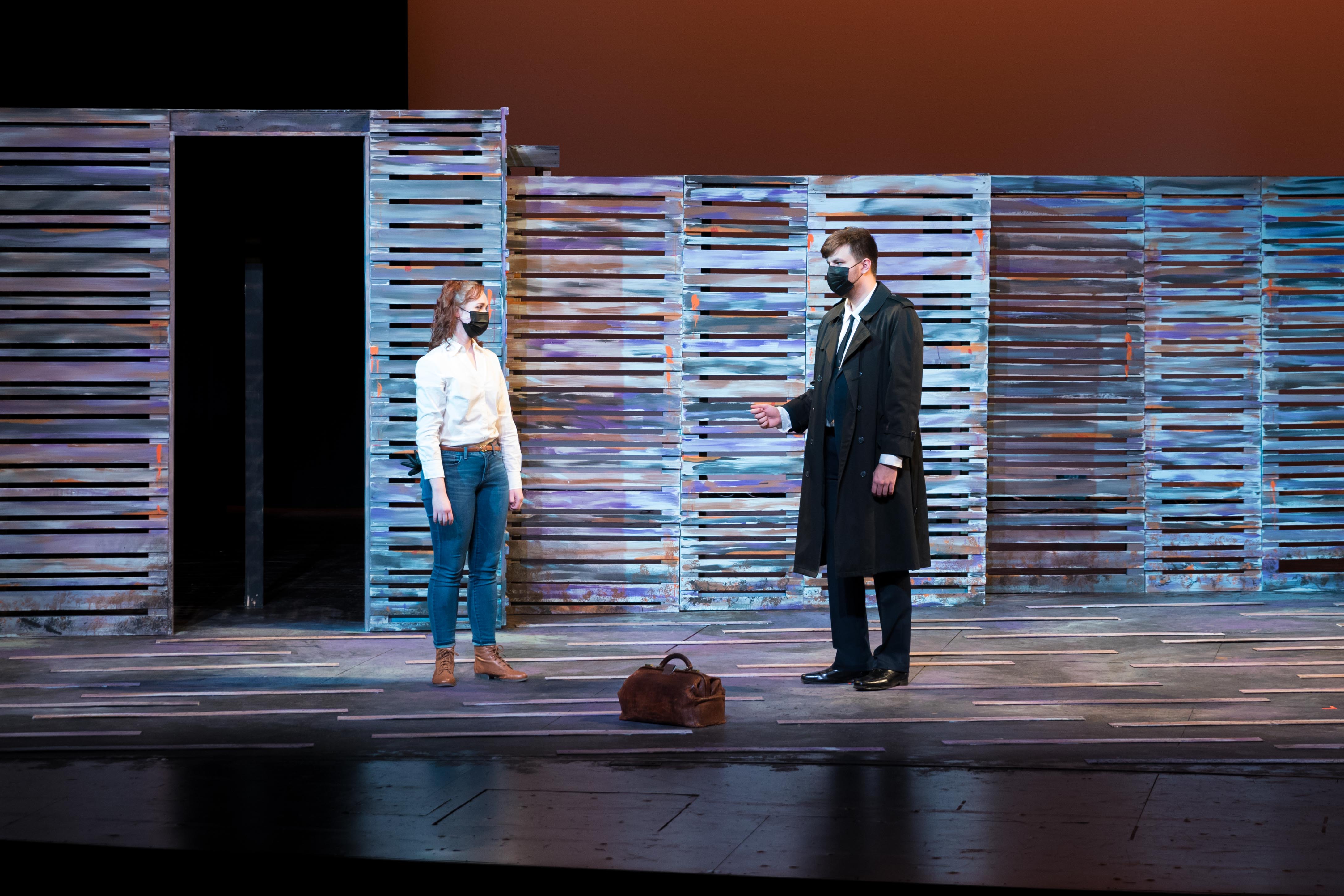 Two people on a stage on opposite sides of a bag.