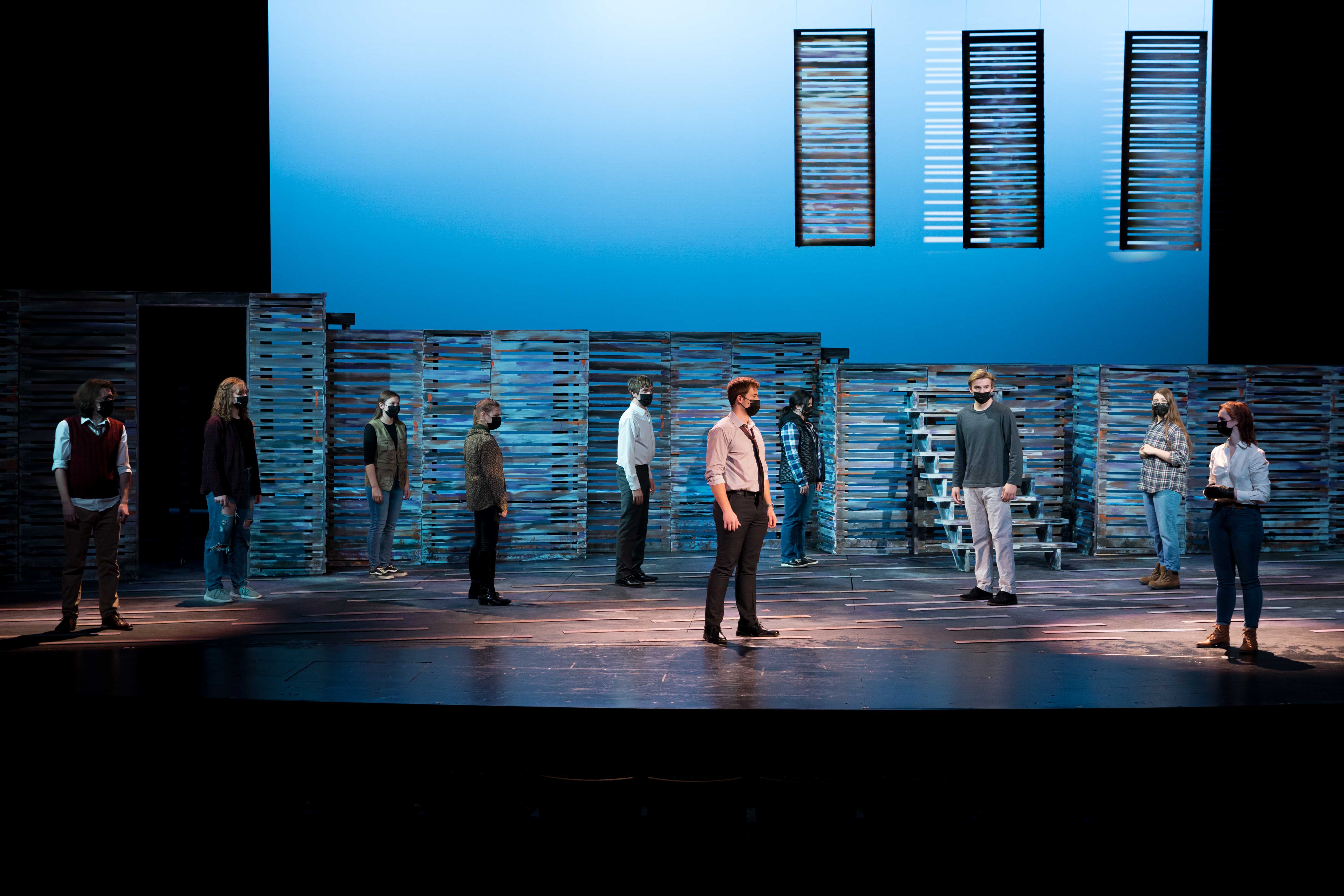 A group of people on a stage under blue light, three under spotlights.
