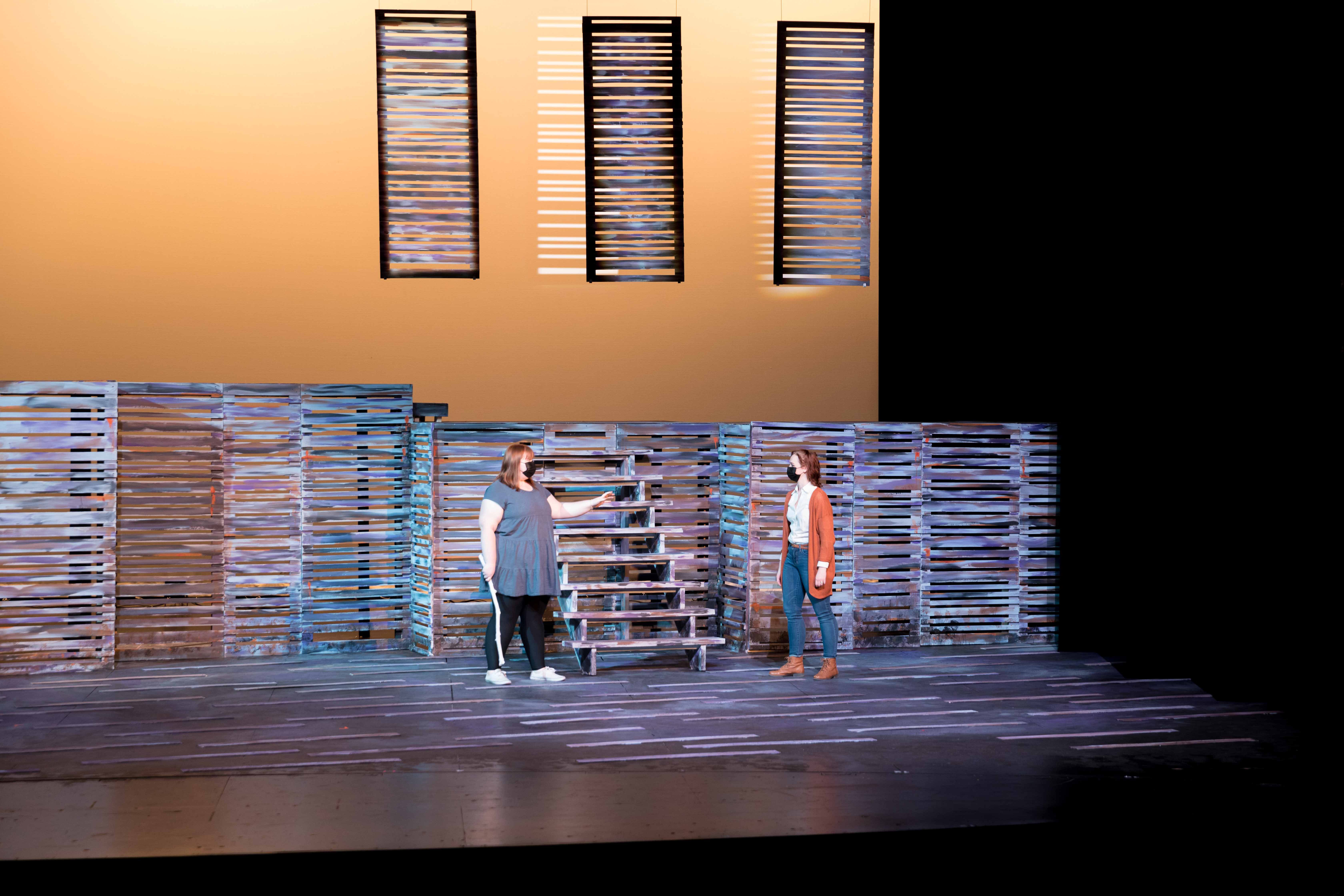 Two people on a stage under orange lighting.