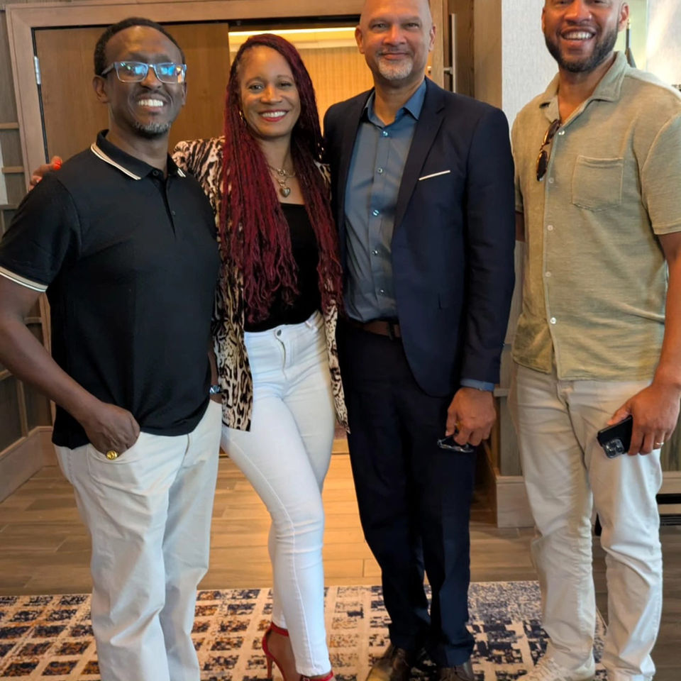 Four smiling individuals: three men and a woman with red hair