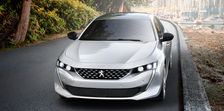 Head-on angle of a Peugeot 508 GT car sitting on a road with a Vancouver marina in the background.