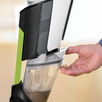 Hand removing holding tank from Bissell Crosswave WetDry Vac