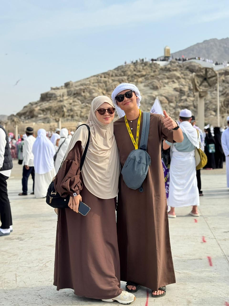 Man and woman pilgrims in brown robes, desert background.