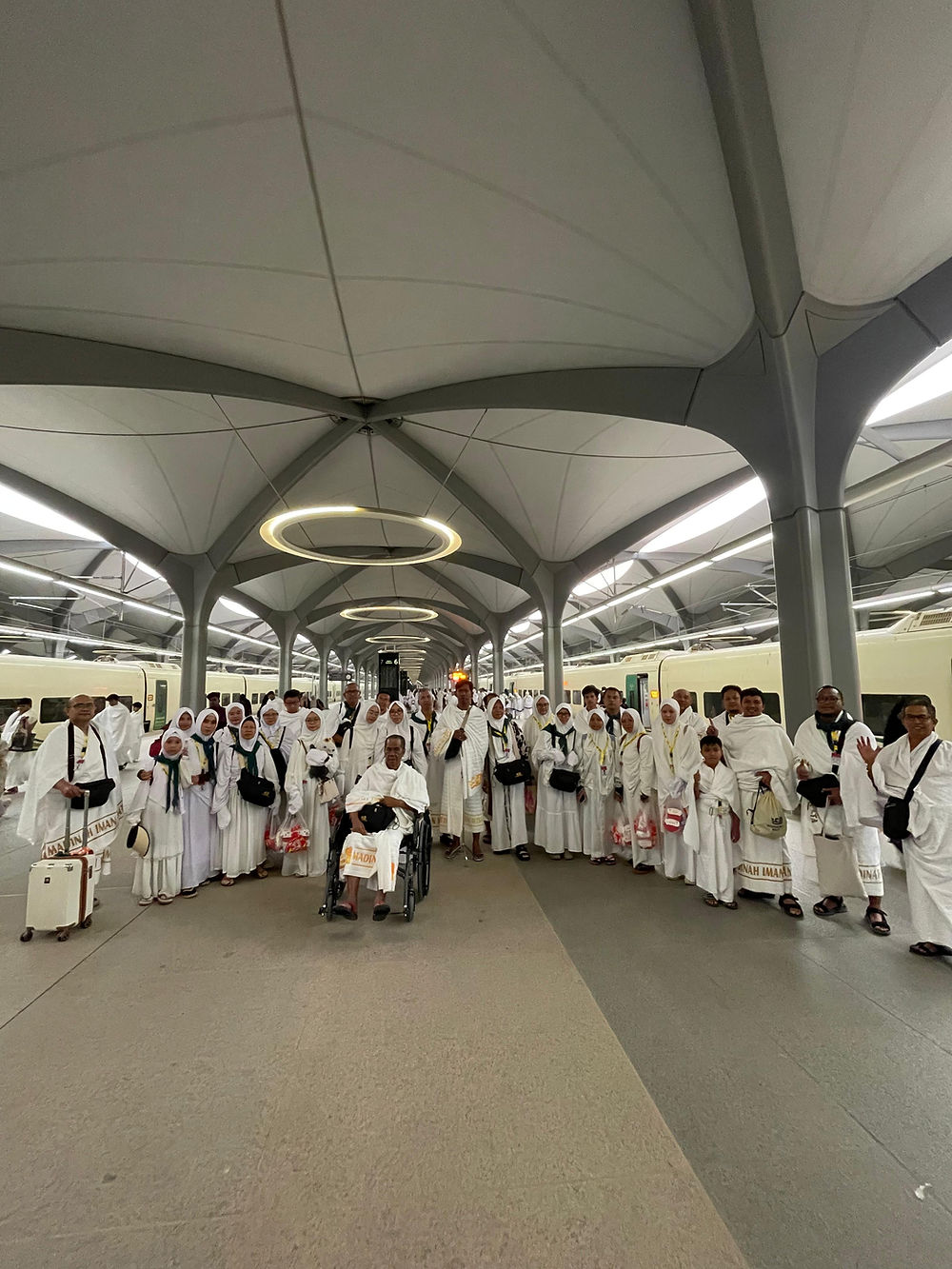 Pilgrims in white, some in wheelchairs, indoors