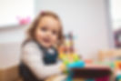 Childcare setting with happy little girl in foreground.jpeg