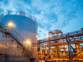 Industrial site with a large storage tank and structures under a twilight sky.