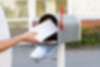 Close-up Of Person Putting Stack Of Letters In Mailbox.jpg