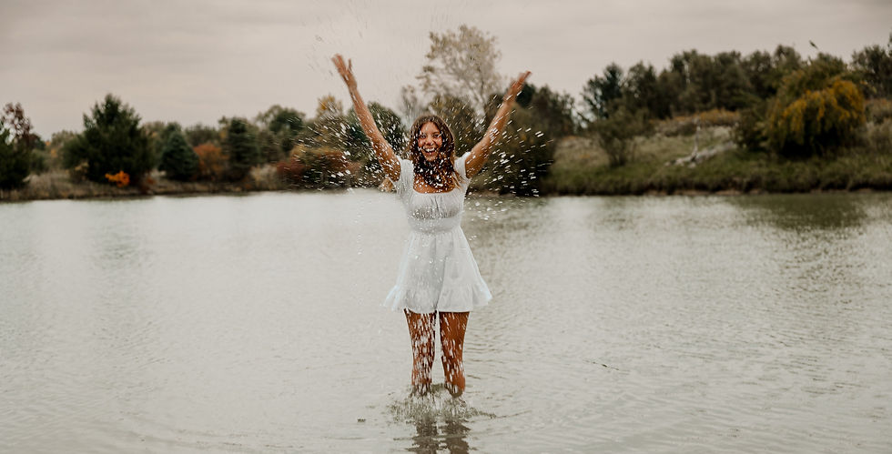 high school senior girl splashes in the lake