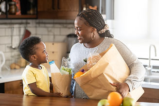 Cheerful African-American mother and son in the kitchen. Son helps a mother to bring in a