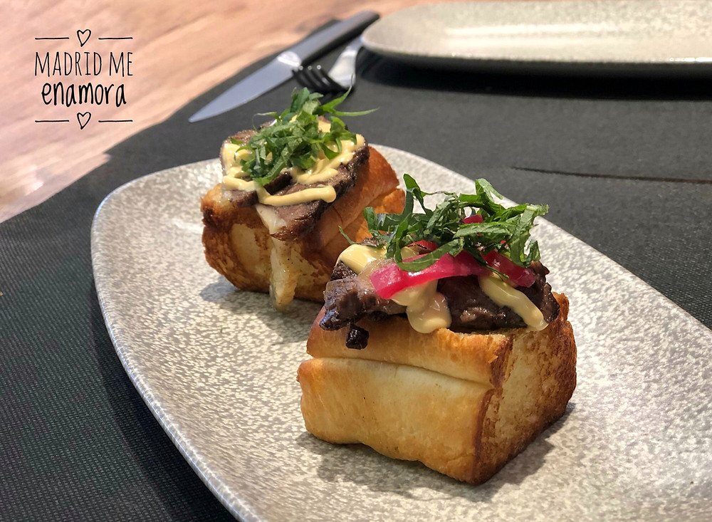 Brioche relleno de costillas de vaca madurada con cebolla encurtida y hoja de shiso verde con mahonesa de soja.
