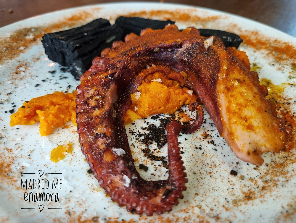 Espetinho de pulpo a la gallega con yuca con tinta de calamar, que simula las brasas.