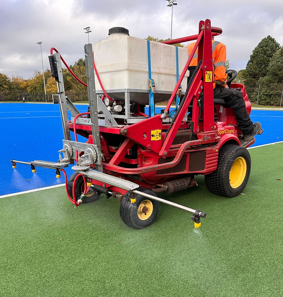 Professional artificial grass maintenance machine operating on a sports surface installation