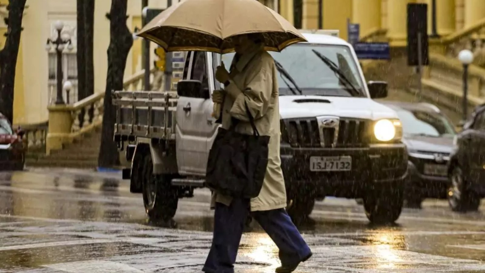 Pessoa se protege da chuva em rua molhada no Rio Grande do Sul