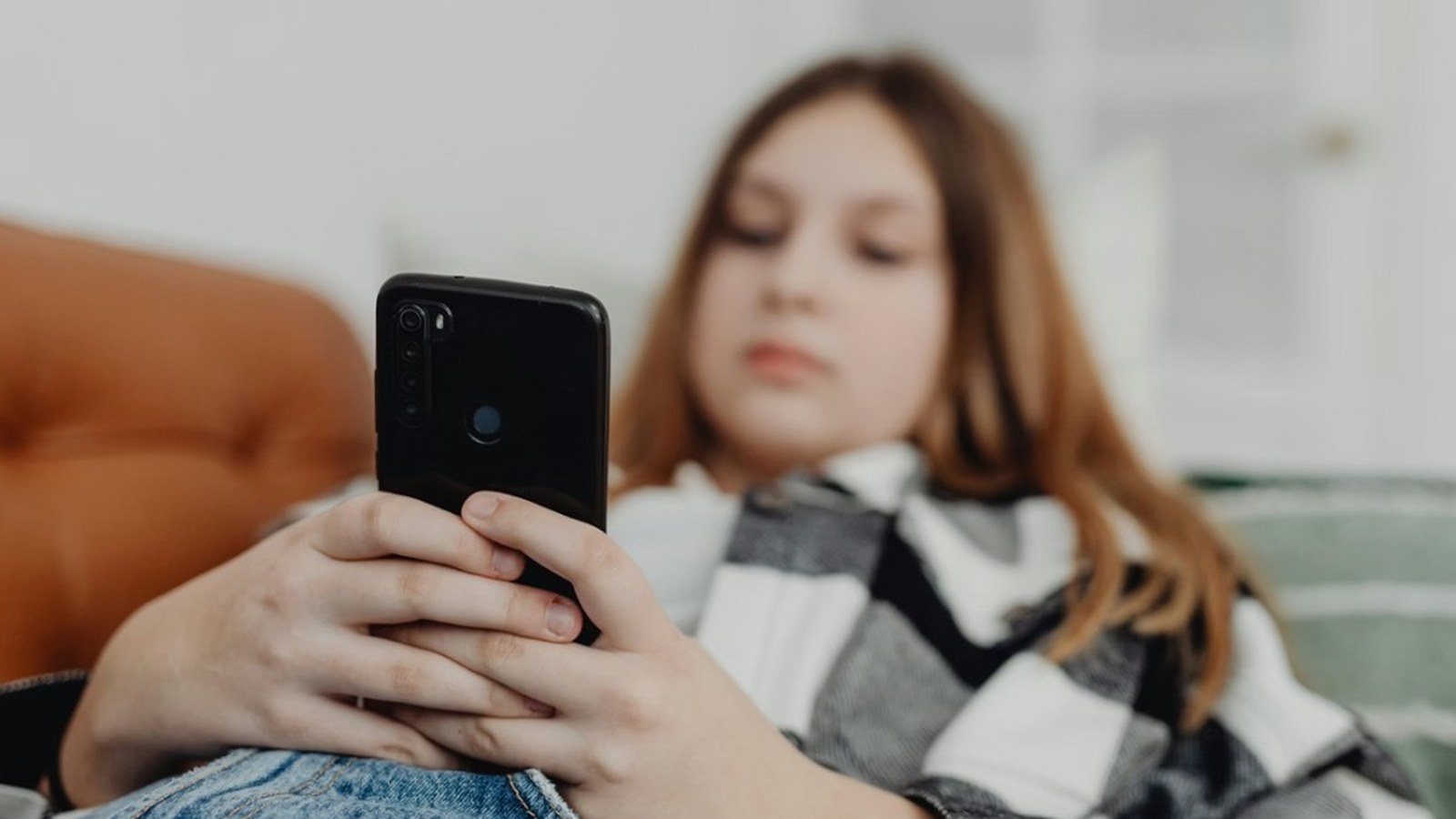 Adolescente usa o celular em casa durante as férias escolares