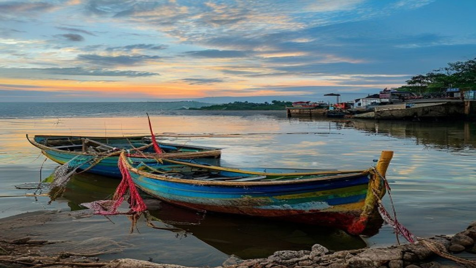 Barcos de pesca artesanal coloridos parados na margem da Lagoa dos Patos ao amanhecer, redes de pesca, sem rostos identificáveis — Pelotas