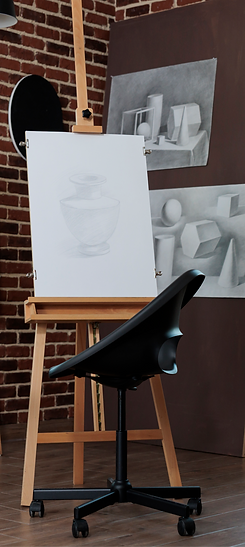 A studio with an Artist's seat in front of a drawing canvas. The walls of the studio are decorated with art pieces created by previous students