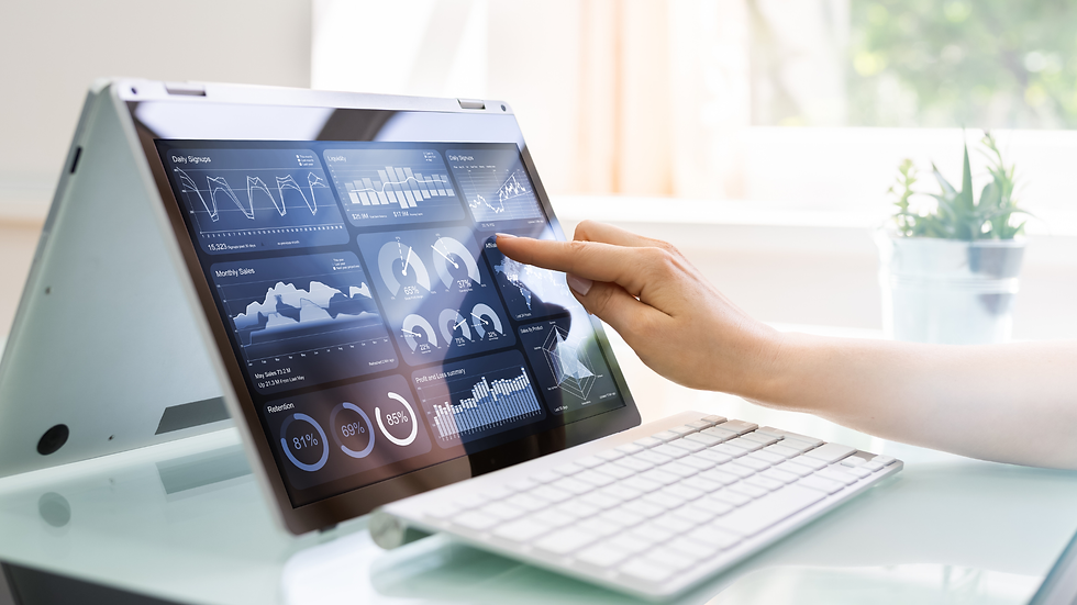 Person touching laptop screen displaying data charts, office environment, white keyboard, plant