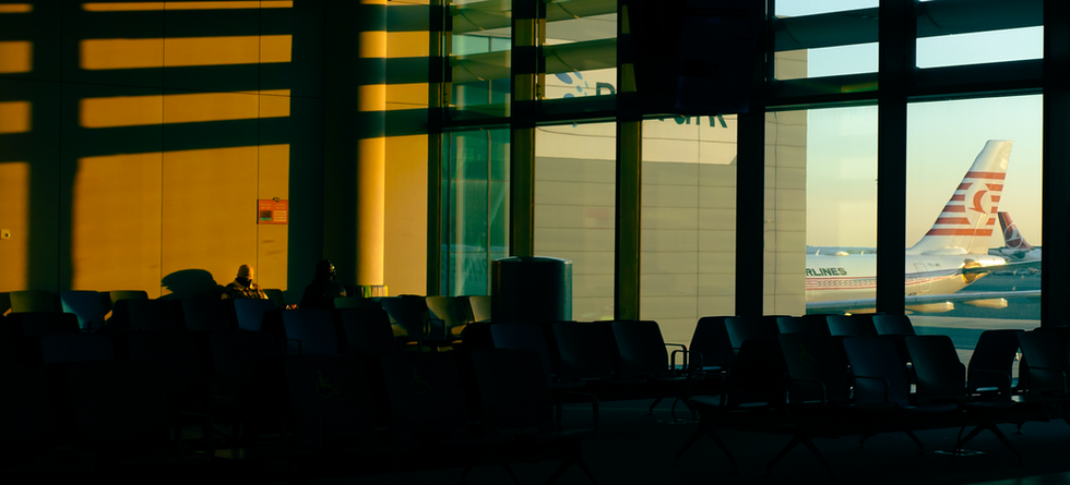 A indoor sunset shot of a man waiting at Istambul airport at sunset, a beautiful airplane in the back in an empty waiting room gate