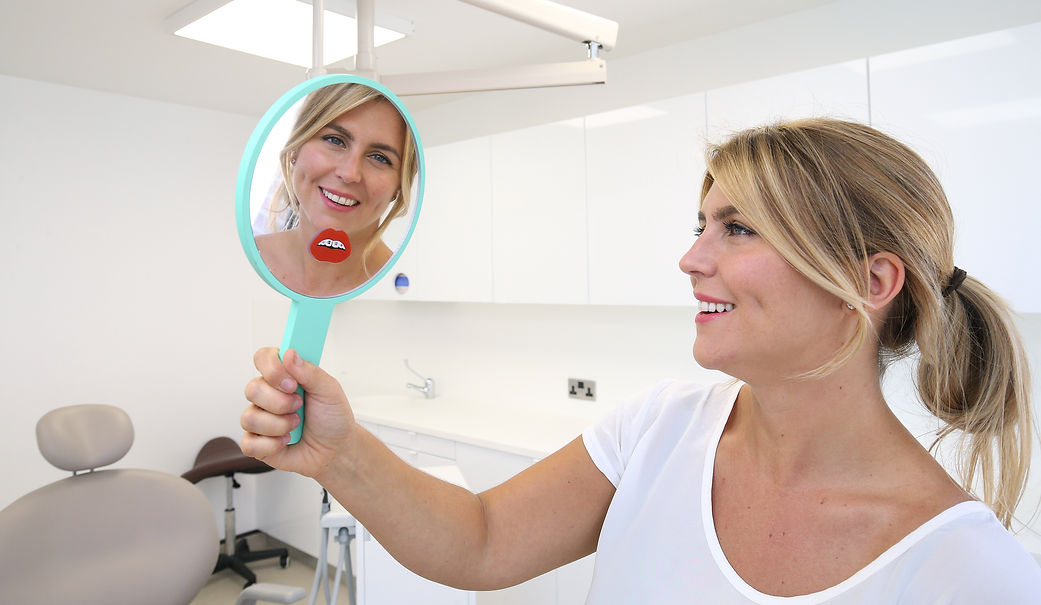 smiling woman looks at new implants in a mirror