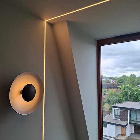 Round designer wall light fixture casting a warm halo glow near an open window view
