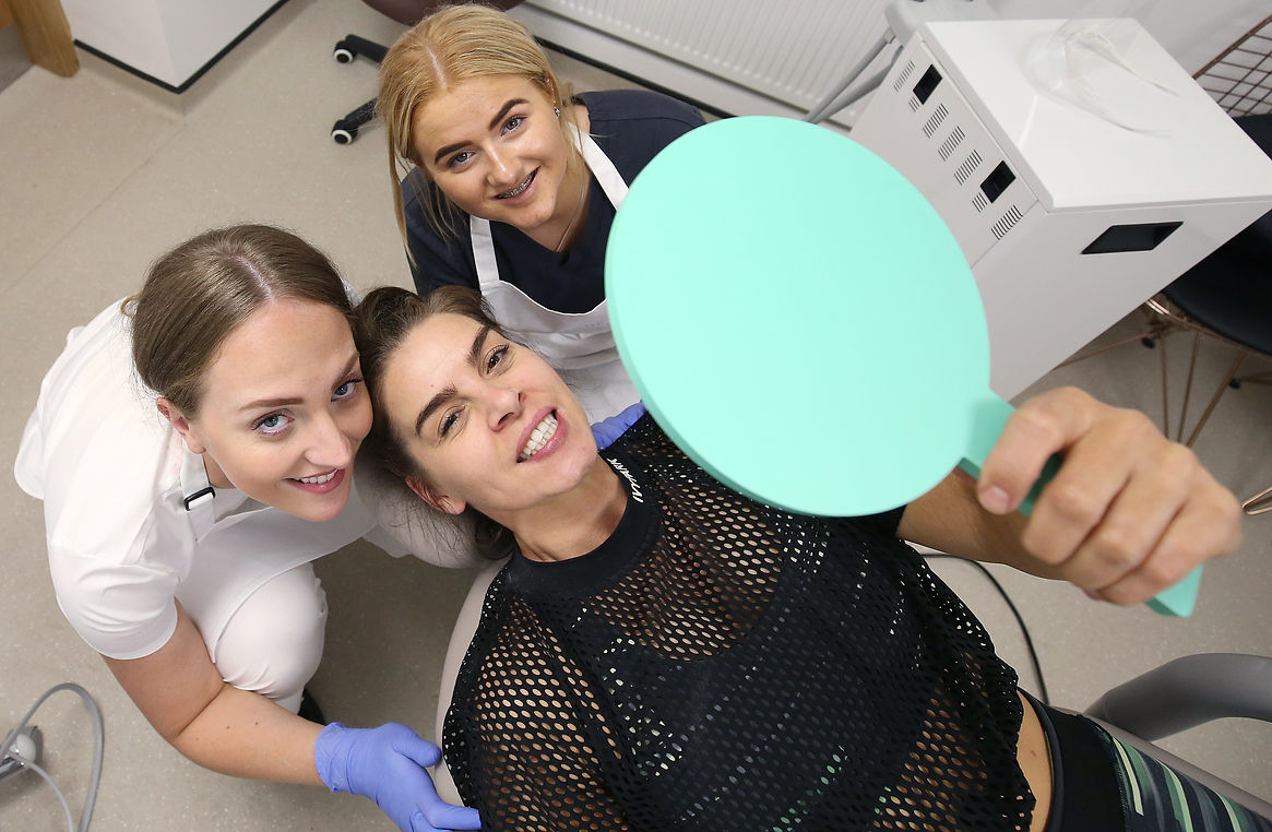 Three women in a dental chair smiling and taking a selfie together, showcasing a fun moment during their dental visit