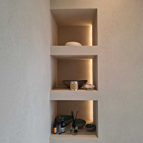 Minimalist alcove shelving built into a neutral textured wall with integrated soft LED strip lighting