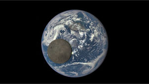 The Moon passes in front of Earth as seen from space, revealing Earth’s bright clouds and oceans contrasted with the Moon’s darker surface.