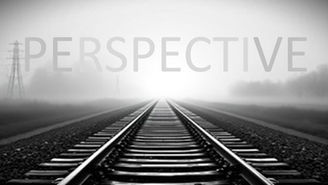 Railway tracks stretching into the distance and appearing to converge at the horizon in a foggy landscape.