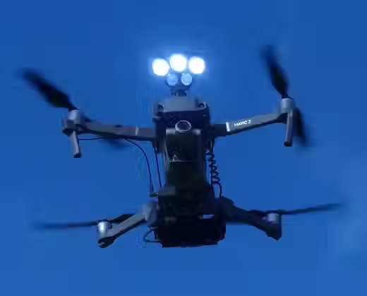 DJI Mavic 2 drone with Drone Sky Hook searchlights mounted on top with plain blue background