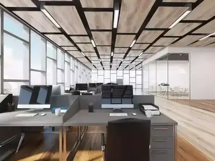 Modern office with empty desks, ergonomic chairs, and gray dividers. Bright overhead lights, colorful ceiling accents, and large windows.