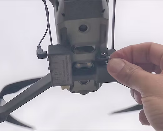 Drone sky hook payload and release mechanism being attached on DJI Mavic 2 drone by a hand