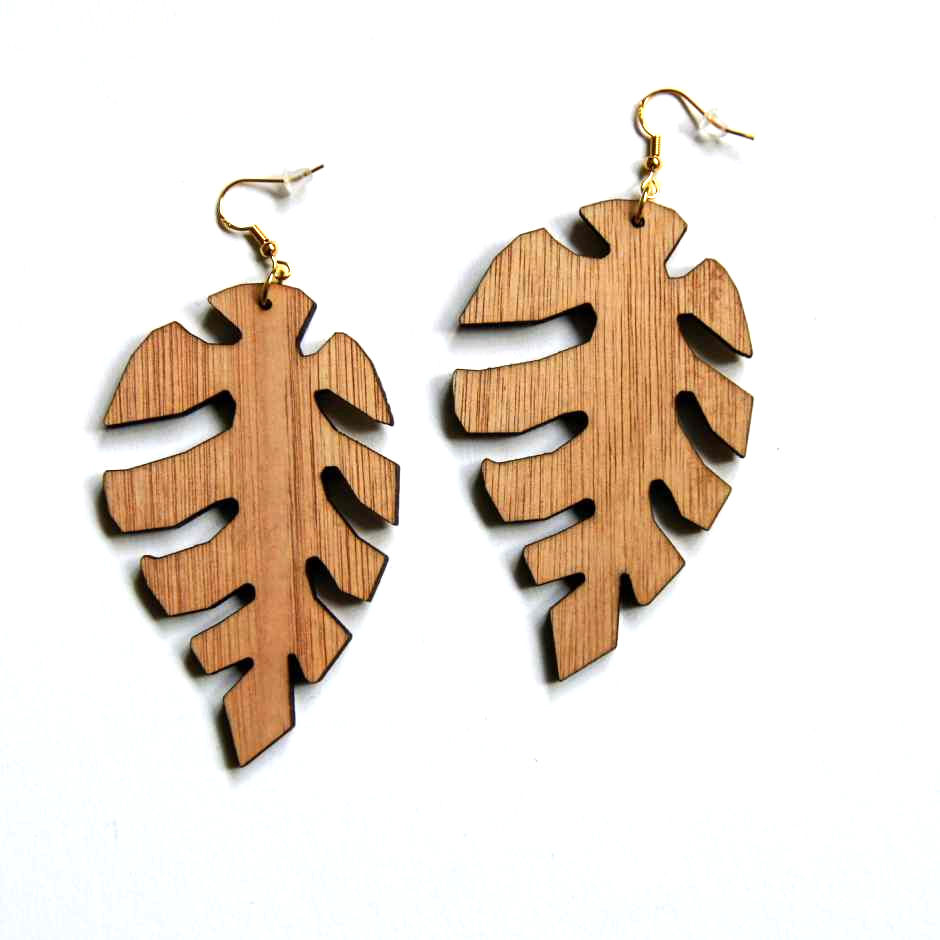 Thumbnail: A pair of Rebel Ear Designs Wooden Monstera Dangle Earrings featuring a large, intricate laser-cut leaf silhouette