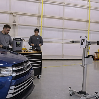 Two auto glass technicians performing ADAS calibration
