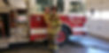 Sam's brother and son in front of a firetruck dressed in fire gear.