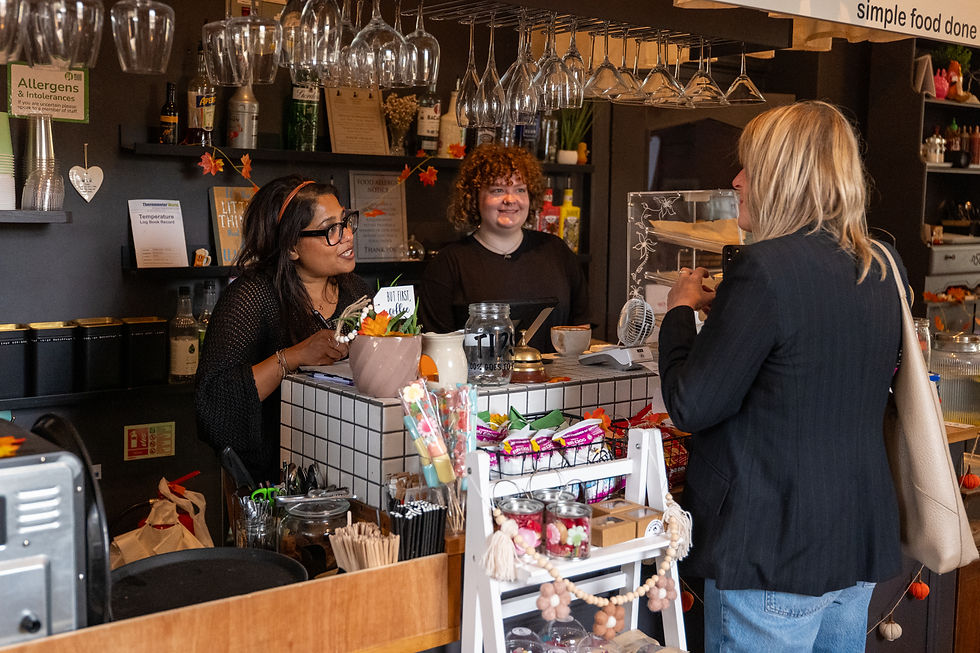 A Cafe owner having a light hearted conversation with a customer who was ordering a cup of coffee and a slice of cake in a bustling community cafe