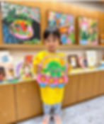 Student displaying an alien and spaceship-themed paper artwork