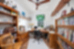 Home office with built-in wood shelving and desk, stained-glass window, ceiling fan, and wood-look flooring