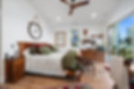 Primary bedroom with vaulted ceiling, wood flooring, stained-glass accent windows, and attached deck access