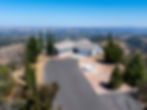 Aerial of the hilltop home, driveway and Italian cypress trees with valley views