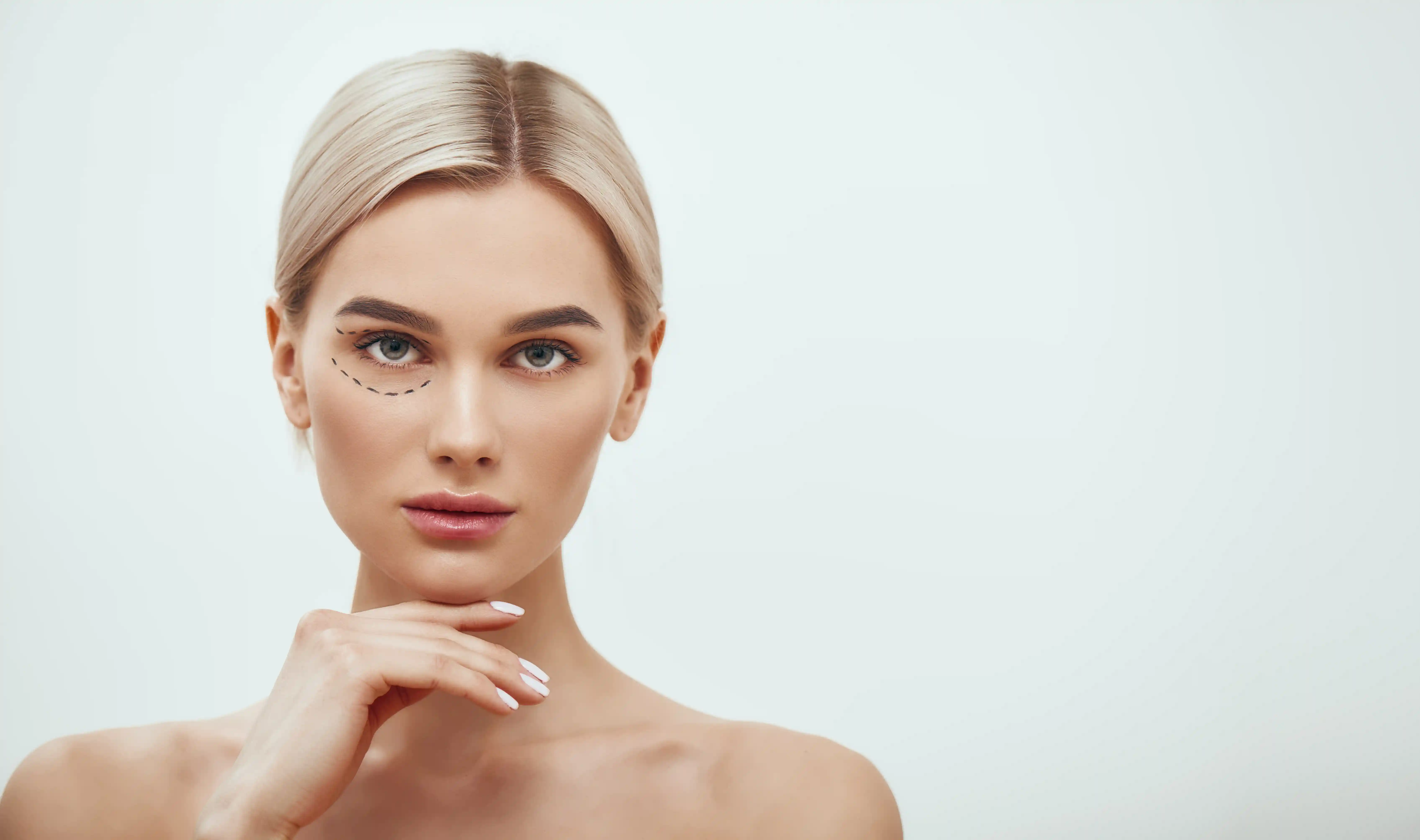A blonde woman face with marked line on her eye area for facelift surgery
