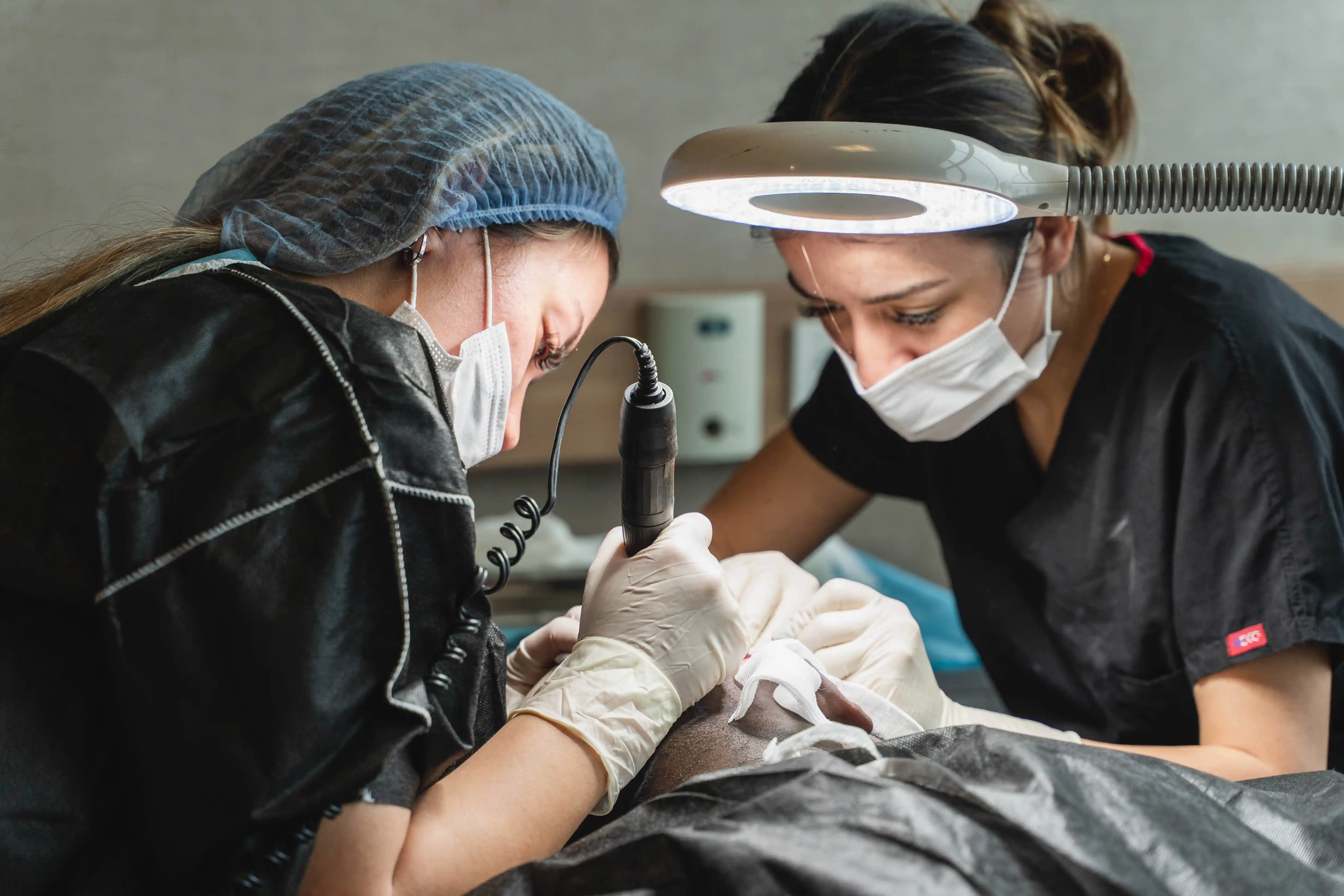 two female doctors during a hair transplant DHI procedure