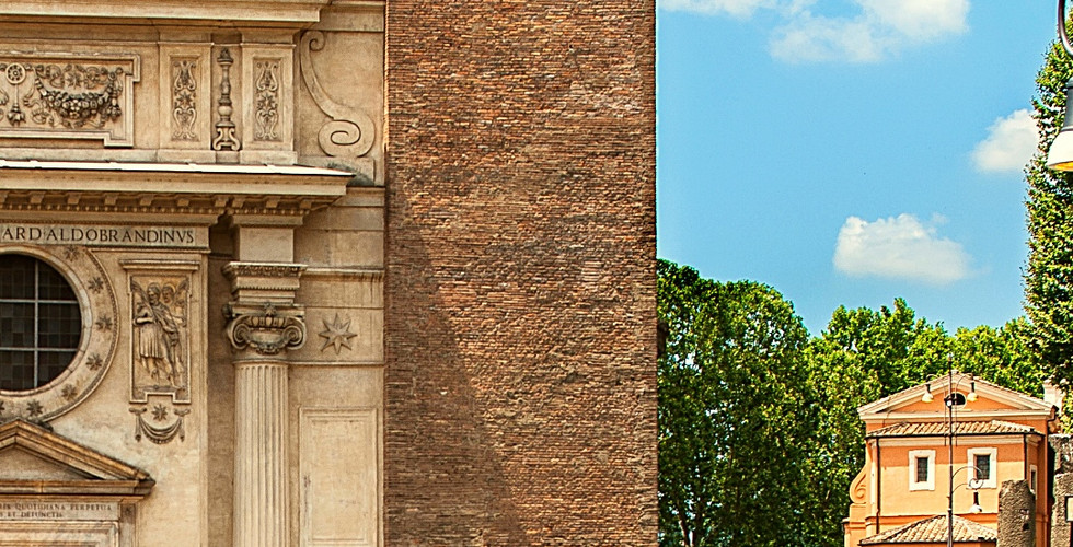 Brick tower and ornate facade of San Nicola in Carcere, Rome, under a blue sky. Text at bottom displays location coordinates.
