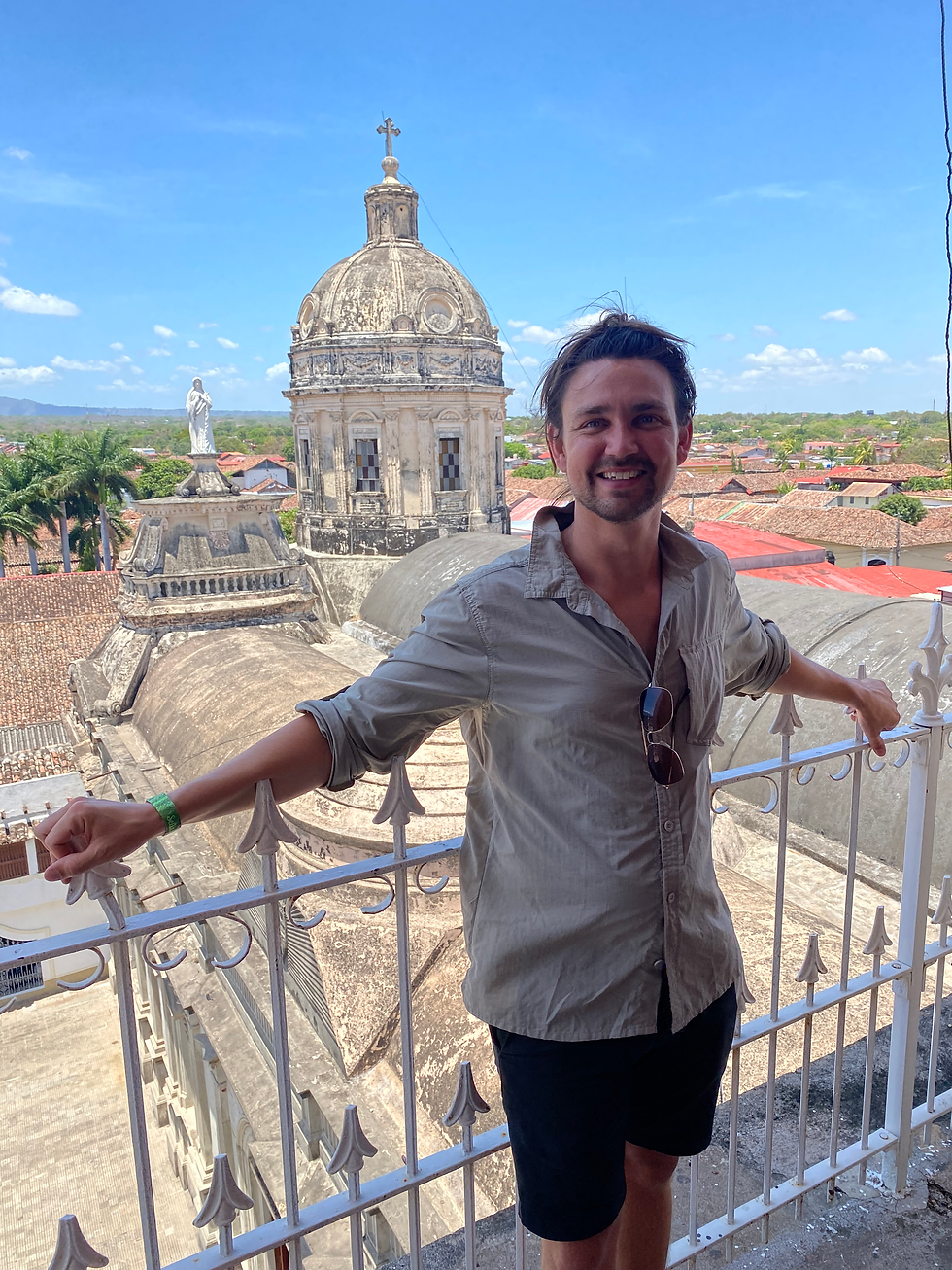 A backpacker looking happy on a rooftop with old buildings behind